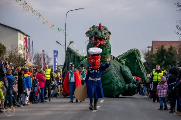 Pust v Cerknici – v ospredju miličnik v modri uniformi z butalsko glavo, v ozadju pa zmaj kot del pustnega karnevala.